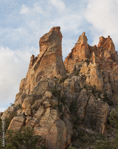 Sandstone towers on Eagle's Crag mountain with the formation known as Mrs. Butterworth in front of the others in Southern Utah with white clouds drifting past