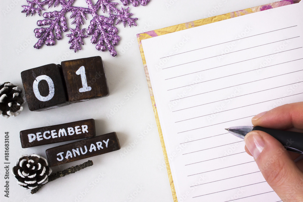 New year greetings in an open notebook, she writes holding a pen New year greetings in an open notebook, she writes holding a pen