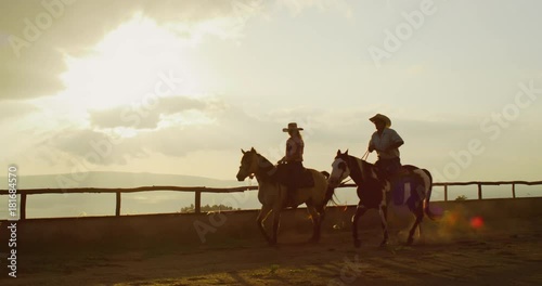 Couple horseback riding together at sunset