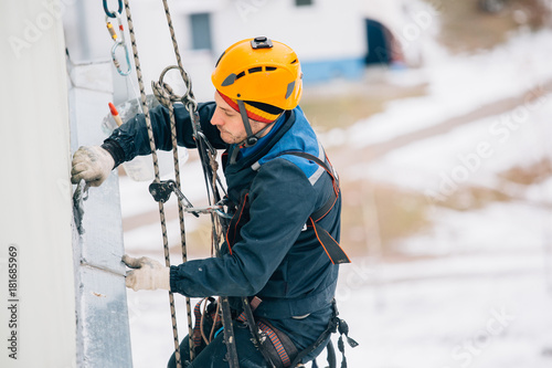 Professional industrial climber in helmet and uniform works at height. Risky extreme job.