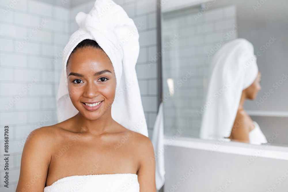 Close up portrait of a beautiful woman in towels wrapped around head and body, standing in bathroom Close up portrait of a beautiful woman in towels wrapped around head and body, standing in bathroom