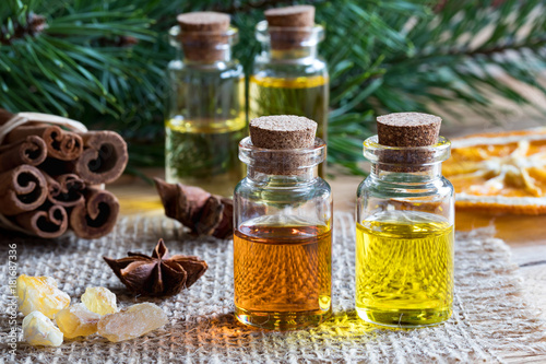 Fototapeta Naklejka Na Ścianę i Meble -  Selection of essential oils with star anise, cinnamon, frankincense and pine branches