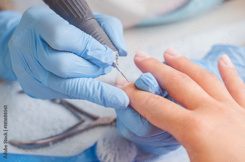 Master of manicure in rubber gloves makes a manicure with the help of a nail polish machine on the nails of a woman Master of manicure in rubber gloves makes a manicure with the help of a nail polish machine on the nails of a woman