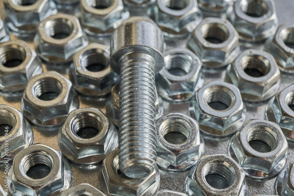 The threaded bolt lies on the shiny hex nuts. Nuts lie in several rows on a metal panel for electrical Cabinet. The nuts round base. Fasteners to building structures. The threaded bolt lies on the shiny hex nuts. Nuts lie in several rows on a metal panel for electrical Cabinet. The nuts round base. Fasteners to building structures.