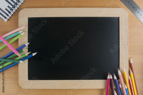Back to school concept: a slate with pencils along with a ruler and a notes