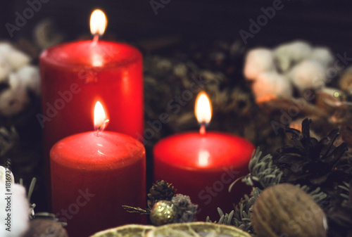 Red candles with a pinecone and natural decorations