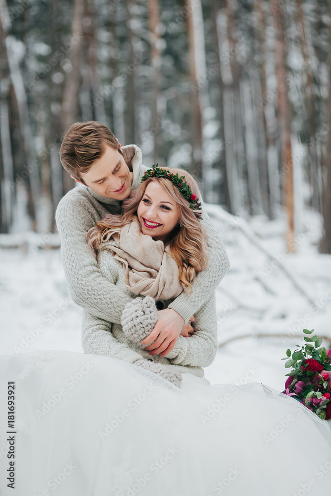 Happy newlyweds are hugging in the winter forest. Couple in love. Winter wedding ceremony.