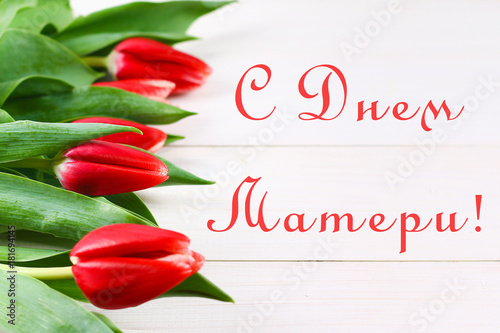 Pink tulips on a white wooden table with an inscription in Russian - Happy Mother's Day.