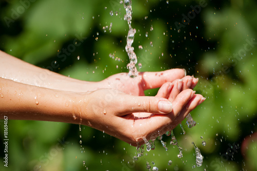 Woman is washing hand outdoors. Young hands with water splash, selective focus. Health concept