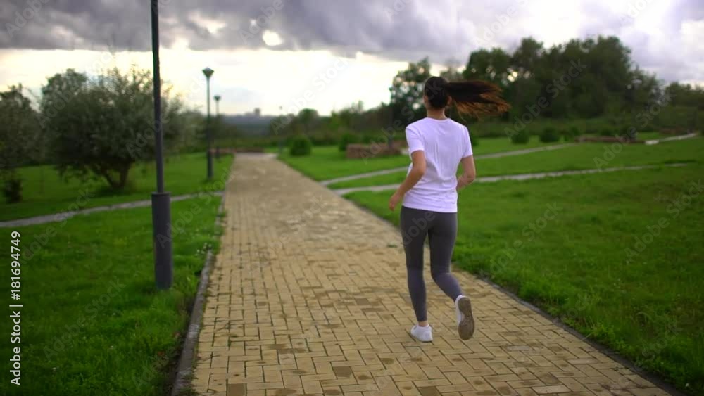 Young beautiful woman is running in the Park. Taken from the back. slow-motion Young beautiful woman is running in the Park. Taken from the back. slow-motion