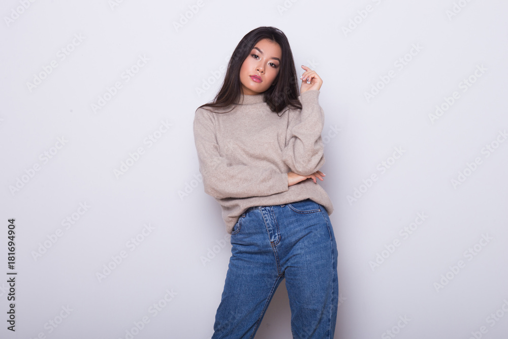 Fashion posing beautiful Asian girl in trendy wearing. Casual wearing in jeans, high heel shoes and sweeter