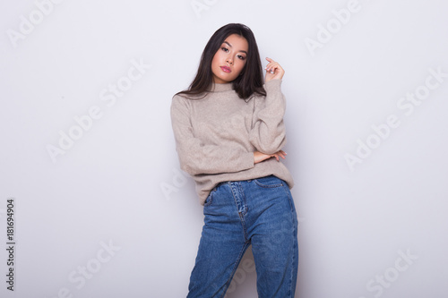 Fashion posing beautiful Asian girl in trendy wearing. Casual wearing in jeans, high heel shoes and sweeter