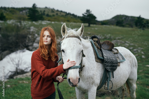Beautiful young woman walking in the mountains with a horse