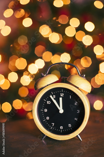 Retro alarm clock on a wooden table bokeh light in background countdown five minutes to midnight