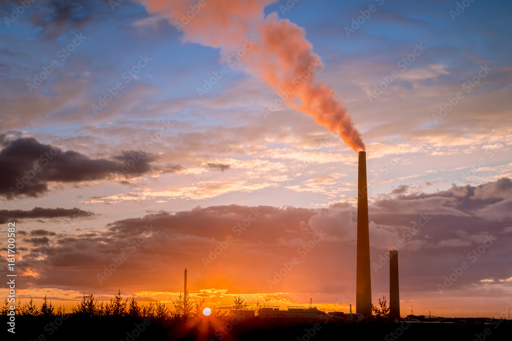 View of a smelter stack of a nickel plant showing the emission on the air with sunset sky as as background