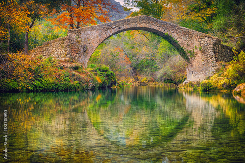 Ancient roman stone bridge Pont des Tuves across the Siagne river surrounded by yellow autumn trees near Saint-Cezaire-sur-Siagne, Alpes Maritimes, France photo