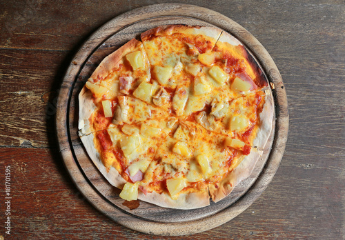 Top view of Delicious homemade pizza served on wood tray against wooden table.