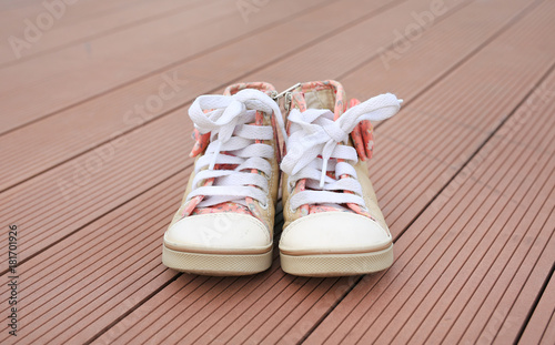 Pair of baby sneakers on wood plank background.
