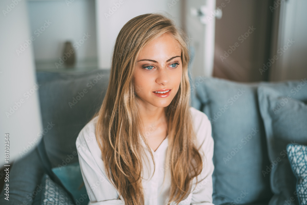Portrait of a young thoughtful blonde woman sitting in the sofa Portrait of a young thoughtful blonde woman sitting in the sofa
