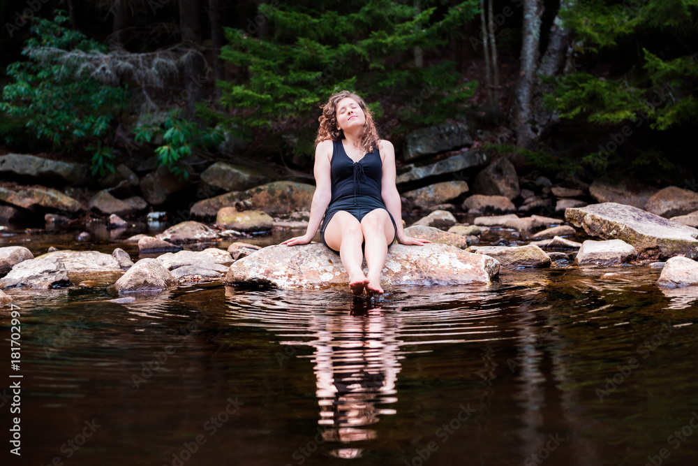 Young woman enjoying nature on peaceful, calm Red Creek river in Dolly Sods, West Virginia during sunny day with reflection dipping feet in water Young woman enjoying nature on peaceful, calm Red Creek river in Dolly Sods, West Virginia during sunny day with reflection dipping feet in water