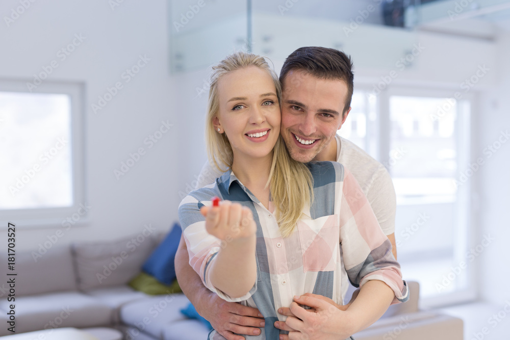 couple showing small red house in hands
