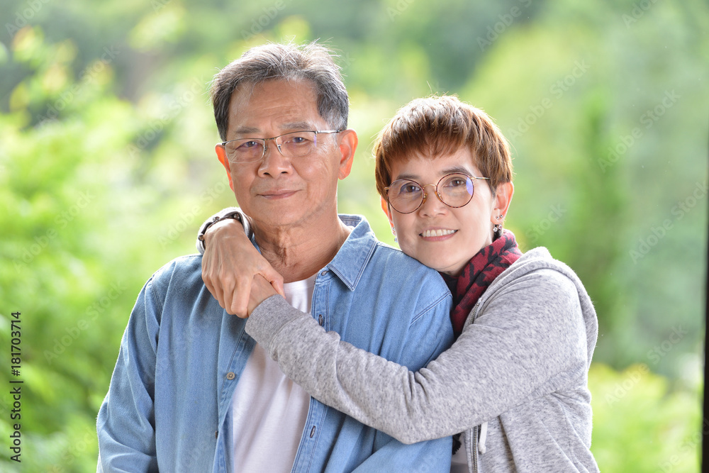 Portrait of happy romantic senior couple looking at the camera on green nature background