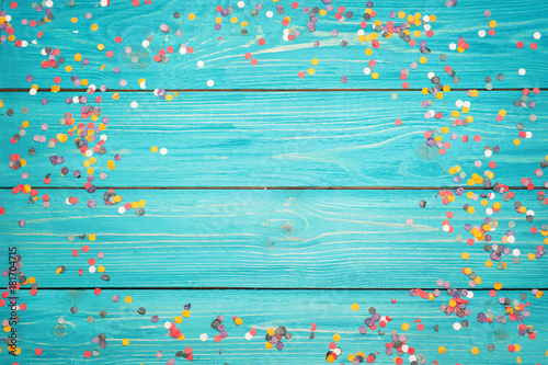 Colorful confetti on a wooden turquoise background .  Free copy space
