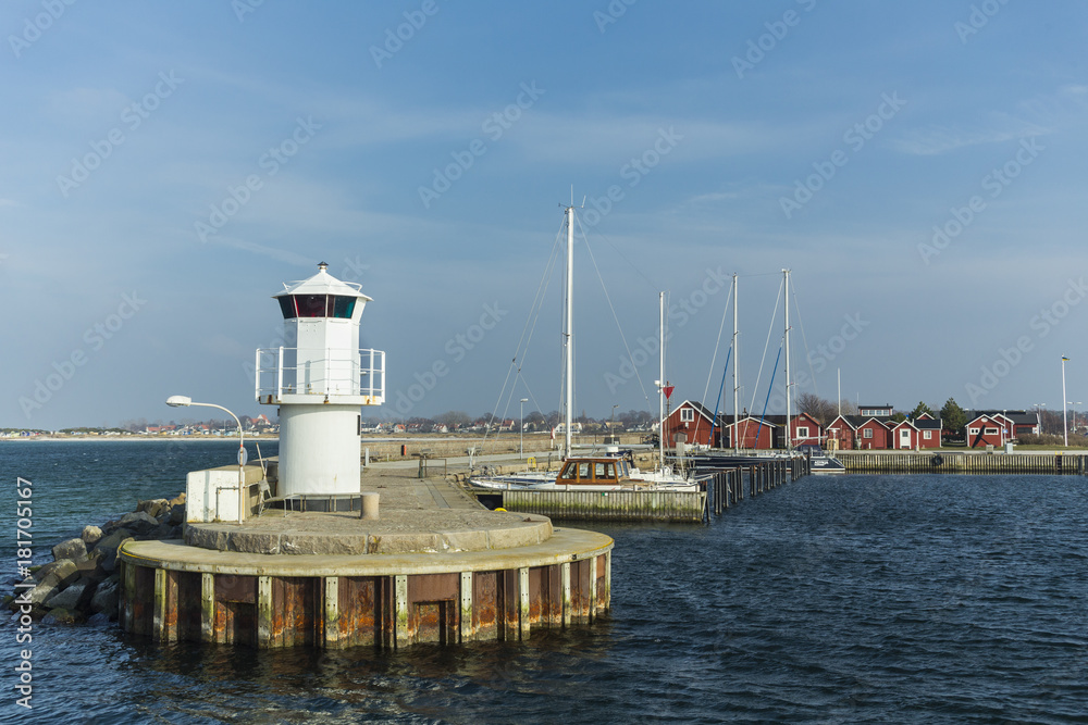 The entrance to a harbour for yachts and boats with a lightroom at the end of a pier