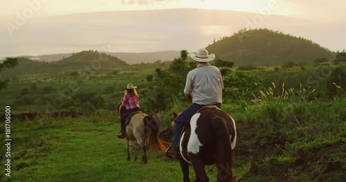 Couple horseback riding together at sunset