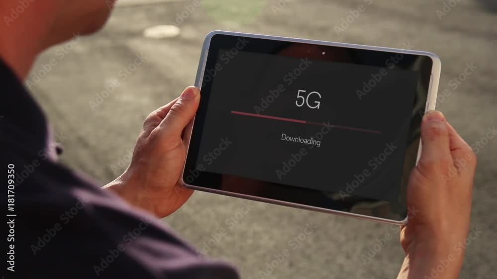 A man downloads a file over 5G cellular data on his handheld tablet.	 	