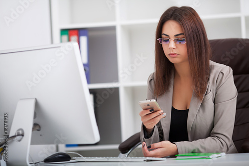 Young business woman working on laptop and talking on mobile phone