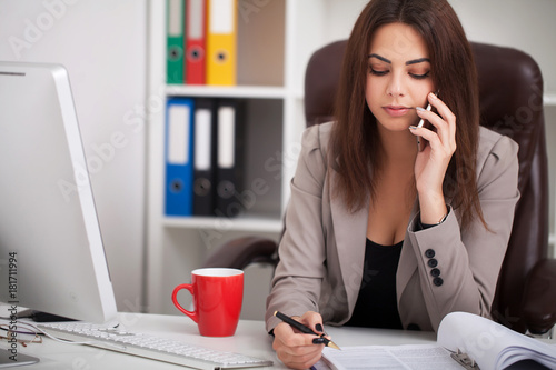 Smiling black businesswoman on phone at desk