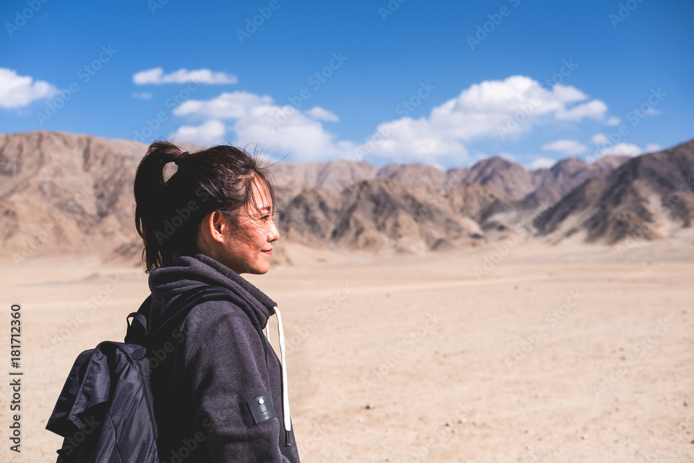 Fototapeta premium Portrait image of a beautiful Asian woman tourist standing in front of mountain and blue sky background