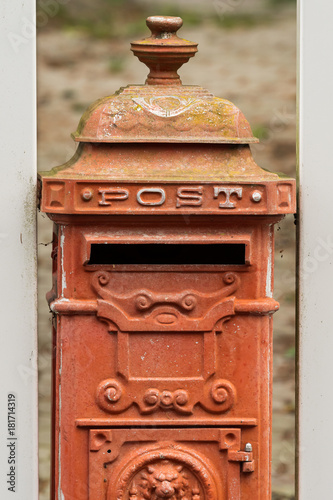 An old red vintage mailbox on a cloudy day