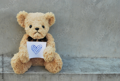 Bear hold paper that has blue heart.