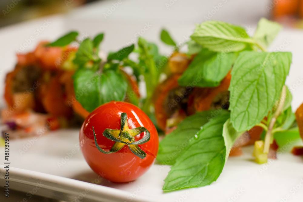 Cherry tomato with fresh vegetables and mint on a white plate