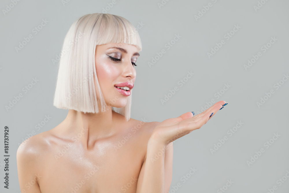Cute Fashion Model Woman Showing Empty Copy Space on the Open Hand. Empty Hand, Shiny Skin and Blonde Bob Hairstyle Cute Fashion Model Woman Showing Empty Copy Space on the Open Hand. Empty Hand, Shiny Skin and Blonde Bob Hairstyle