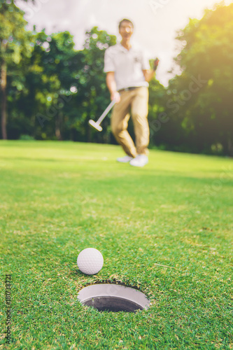 Happiness winner man golfer putting a golf ball in to hole. close up golf ball