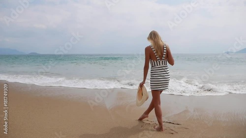 Young woman in black and white dresses walking alone on a tropical beach and watching the storm on the sea. Travel Concept. photo