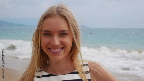 Closeup cheerful young beautiful girl smiling winking looking at camera over background at storm on the sea photo