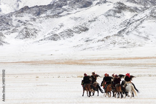 Mongolian horse riders dash between the snowy mountains in the winter of mongolia during the golden eagle festival