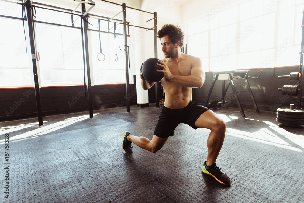 Muscular man exercising with medicine ball at gym Muscular man exercising with medicine ball at gym
