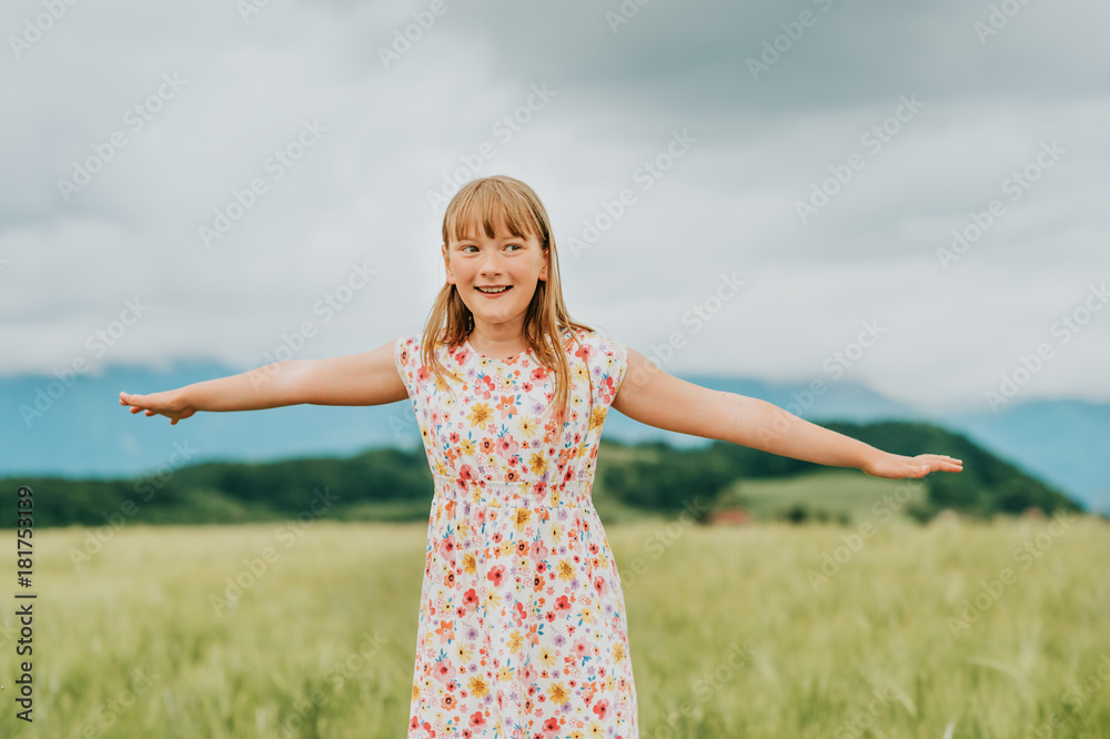 Little girl playing in green wheat field in summertime, wearing a dress, arms wide open Little girl playing in green wheat field in summertime, wearing a dress, arms wide open