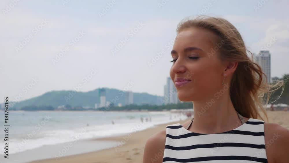 Young woman in black and white dresses walking alone on a tropical beach and looking at camera over background at storm on the sea. Travel Concept. Young woman in black and white dresses walking alone on a tropical beach and looking at camera over background at storm on the sea. Travel Concept.