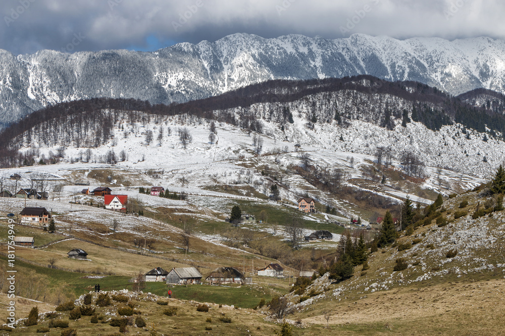 Winter rural landscape with traditional farm houses near Piatra Craiului massif in Sirnea village, Brasov county.