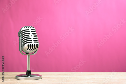Retro microphone on wooden table with pink wall background