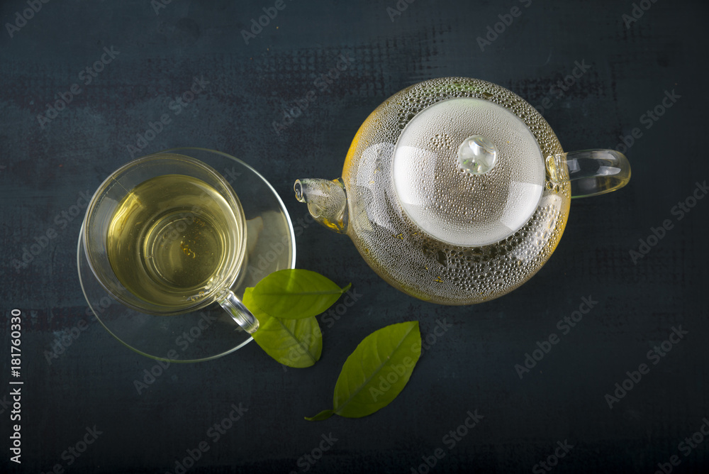 Tea cup with and tea leaf sacking on the wooden table and the tea plantations background Tea cup with and tea leaf sacking on the wooden table and the tea plantations background