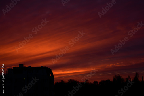 Dramatic and bright sunset. Dark ground. Orange clouds. photo