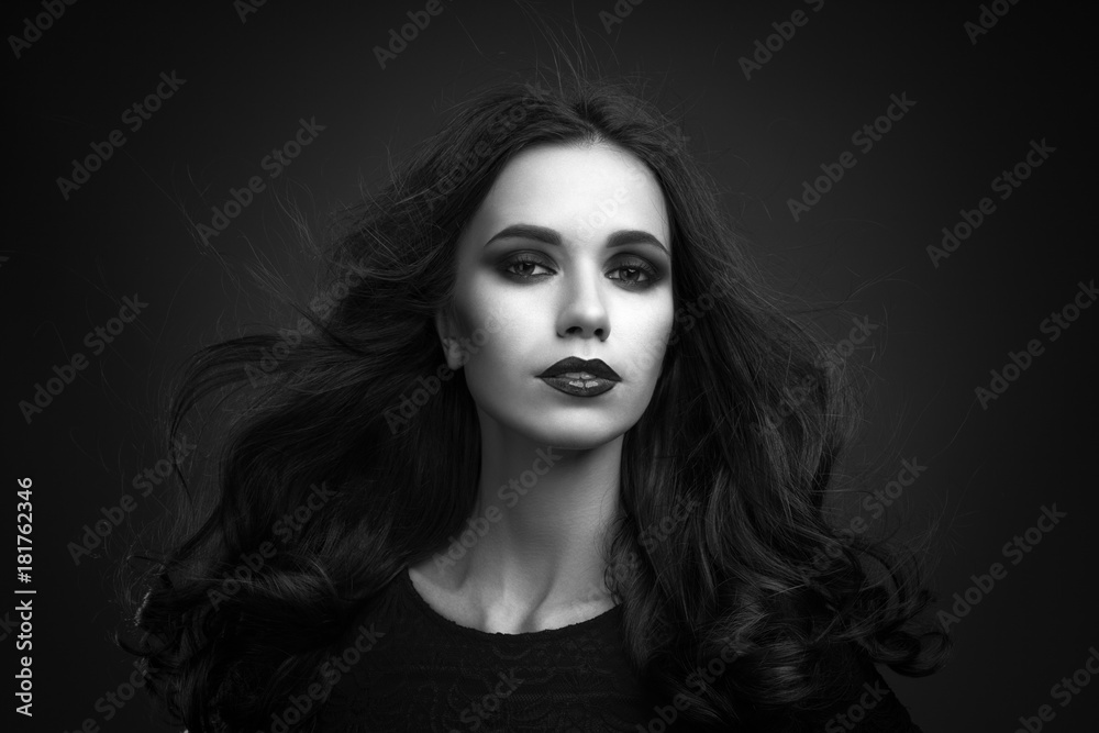 Portrait of the beautiful young woman with long brown hair posing at studio