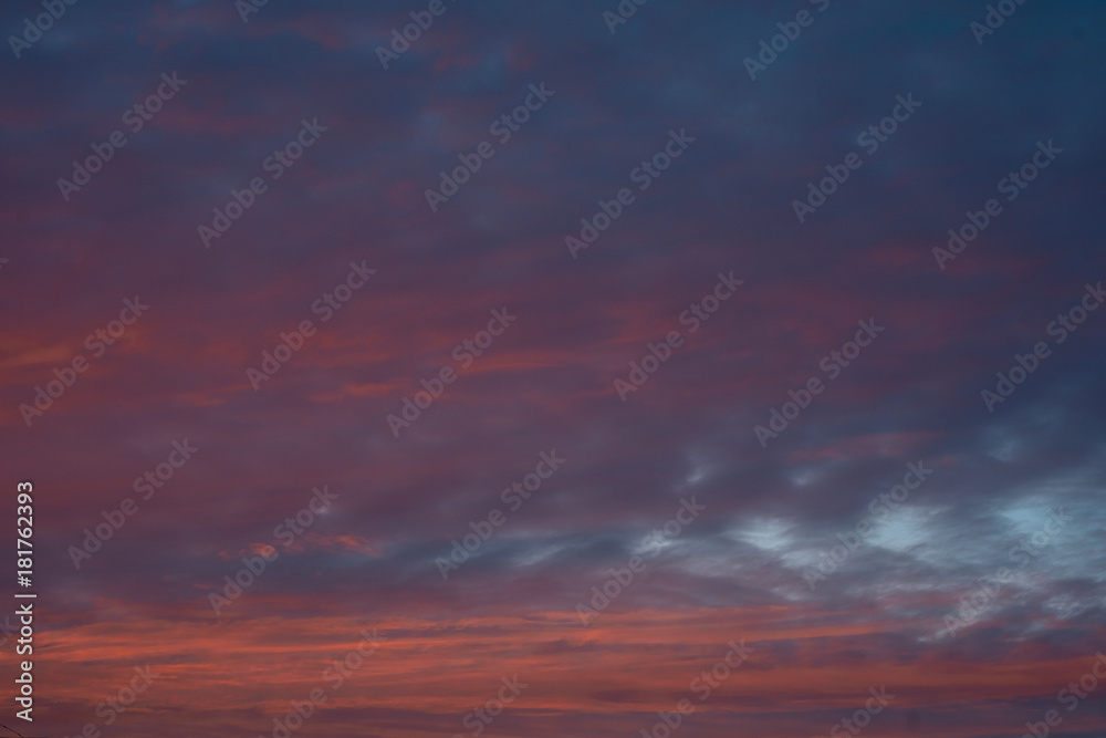 Dramatic colorful sunset sky with clouds. Blue background.